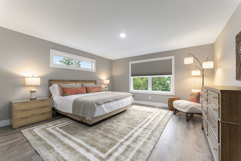 Bedroom with bed, two bedside lamps, chair and windows
